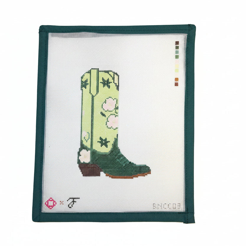 Cross-stitched green cowboy boot with floral patterns on a white fabric background