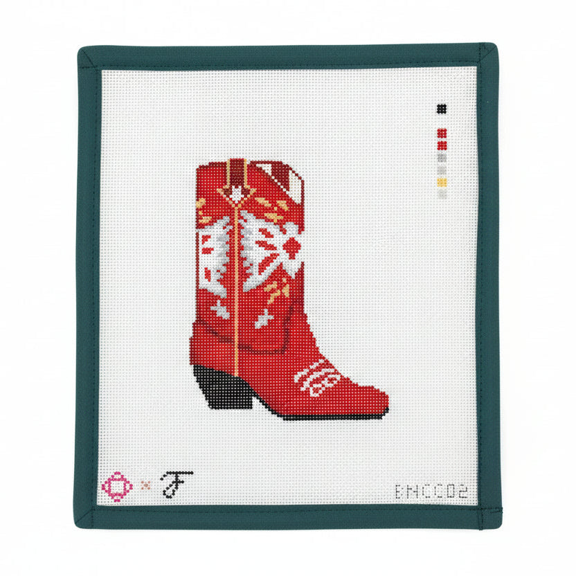 Cross-stitched red cowboy boot on a white fabric with green frame